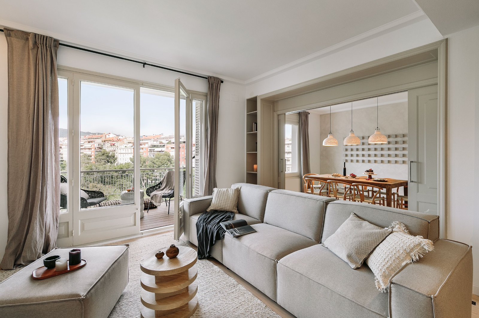 A cozy living room featuring a couch and coffee table, with a panoramic view of the city skyline through large windows.