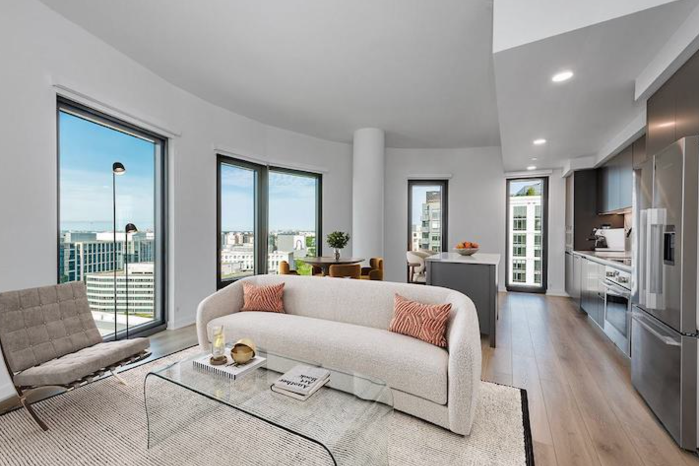 A modern living room featuring a couch, coffee table, and large windows allowing natural light to fill the space.